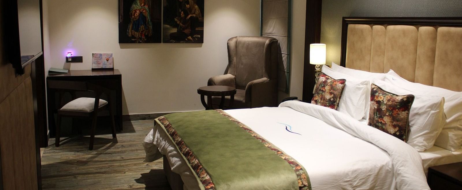 Side view of a bedroom featuring a working table, a chair, and portraits adorning the wall at BluSalzz Residence, Amritsar